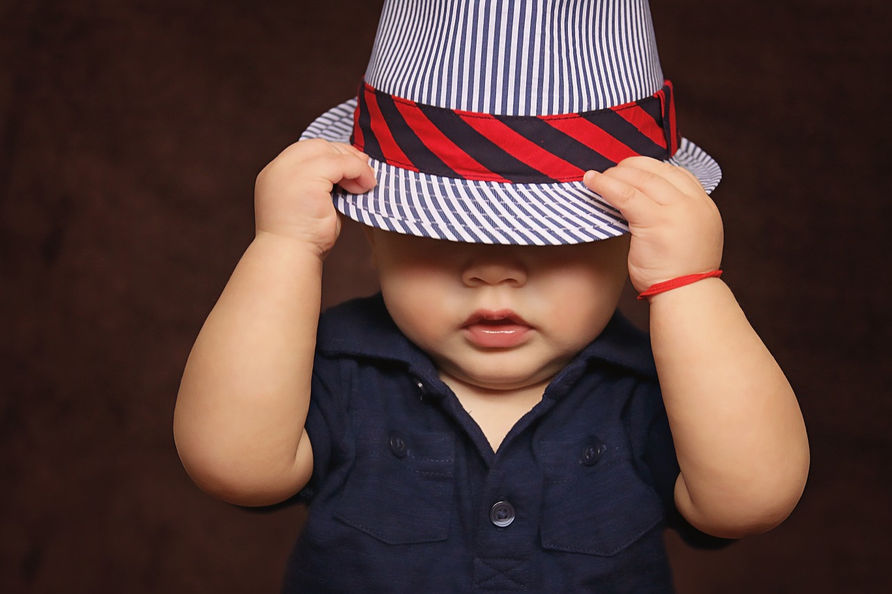 Image - baby boy hat covered eyes playing