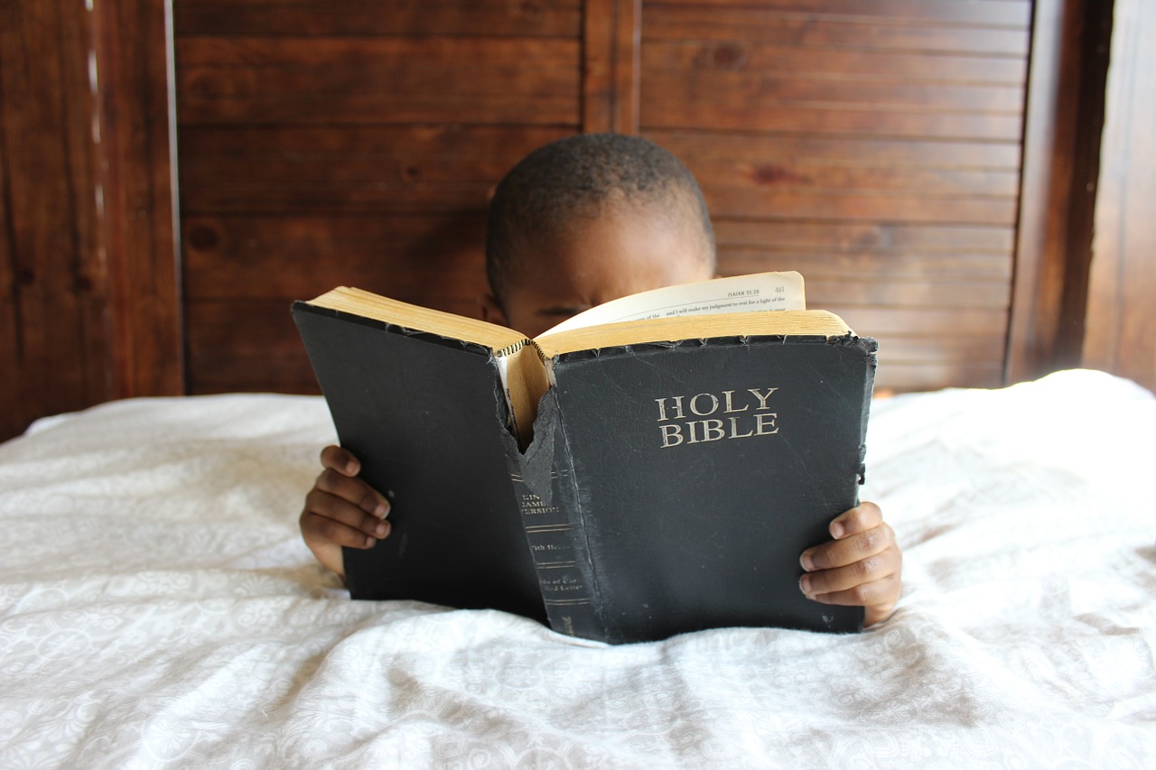 Image - child reading bible bed african